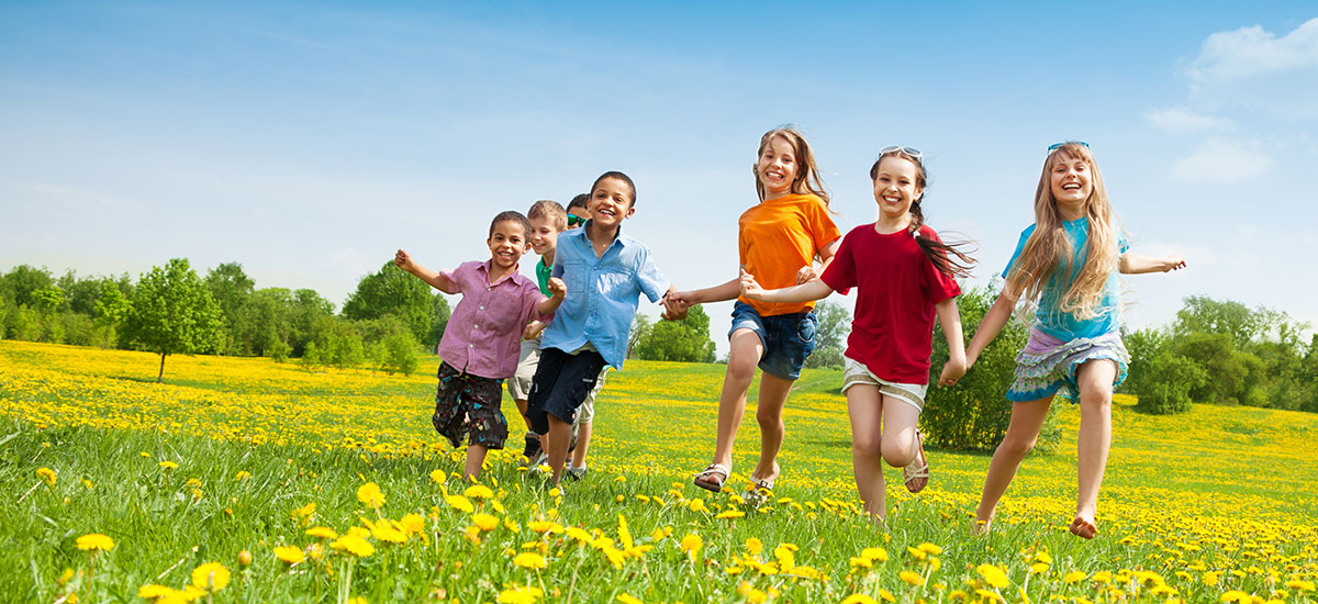 happy and healthy kids running across a field holding hands