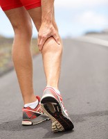 A runner massaging his calf after a sudden injury mid-run