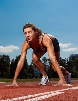Female runner crouches in readiness on the start line of a race