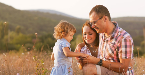 Little girl showing flower to kneeling parents.